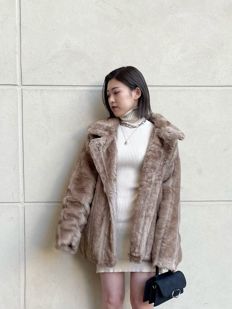 ブラック系のブーツ、ベージュ系のその他アウター、ホワイト系のワンピースを着用したレディースの冬コーディネートの6枚目の写真