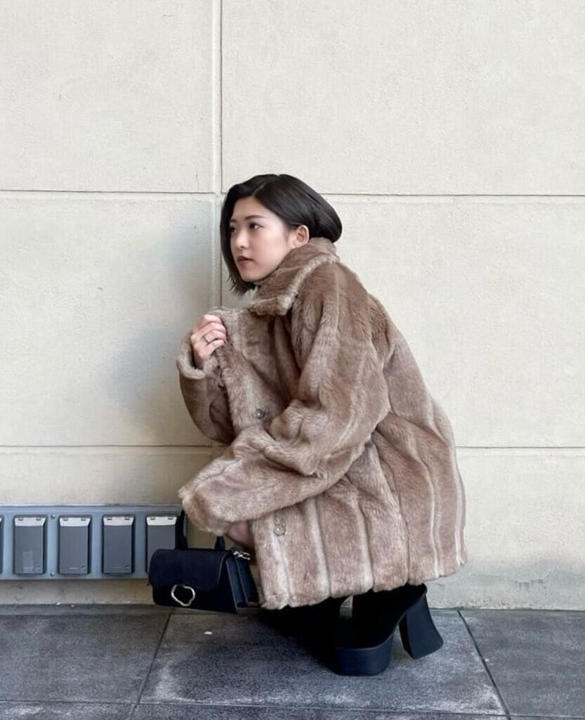 ブラック系のブーツ、ベージュ系のその他アウター、ホワイト系のワンピースを着用したレディースの冬コーディネートの5枚目の写真