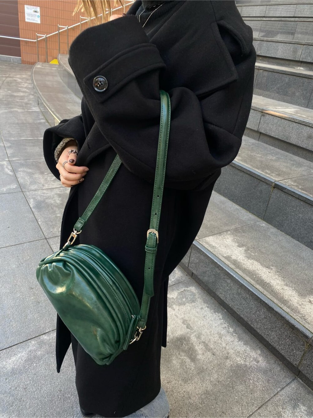 ブルー系のデニムパンツ、ブラック系のニット/セーター、ブラック系のチェスターコートを着用したレディースの秋コーディネートの3枚目の写真
