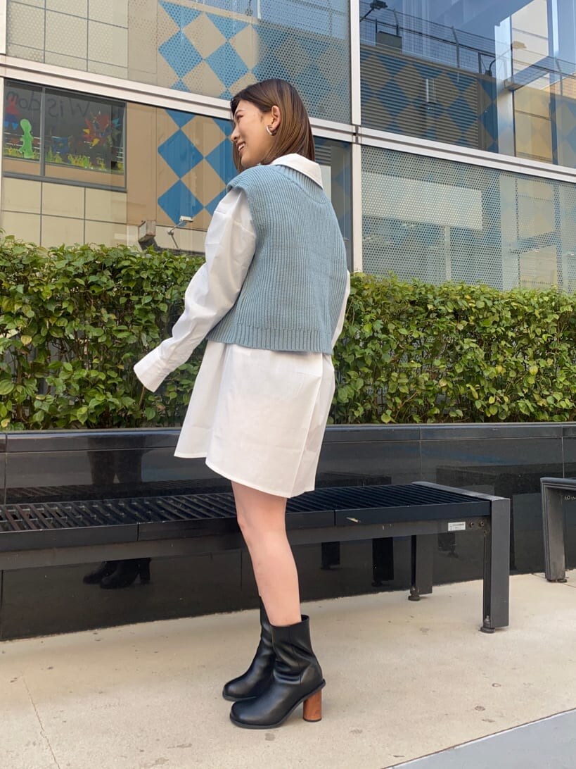 ホワイト系のシャツ/ブラウス、ブラック系のブーツ、ブルー系のベストを着用したレディースの春コーディネートの2枚目の写真