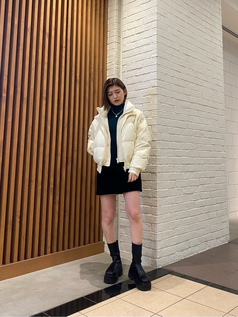 ブラック系のスカート、ホワイト系のダウンジャケット/コート、グリーン系のニット/セーターを着用したレディースの冬コーディネートの5枚目の写真