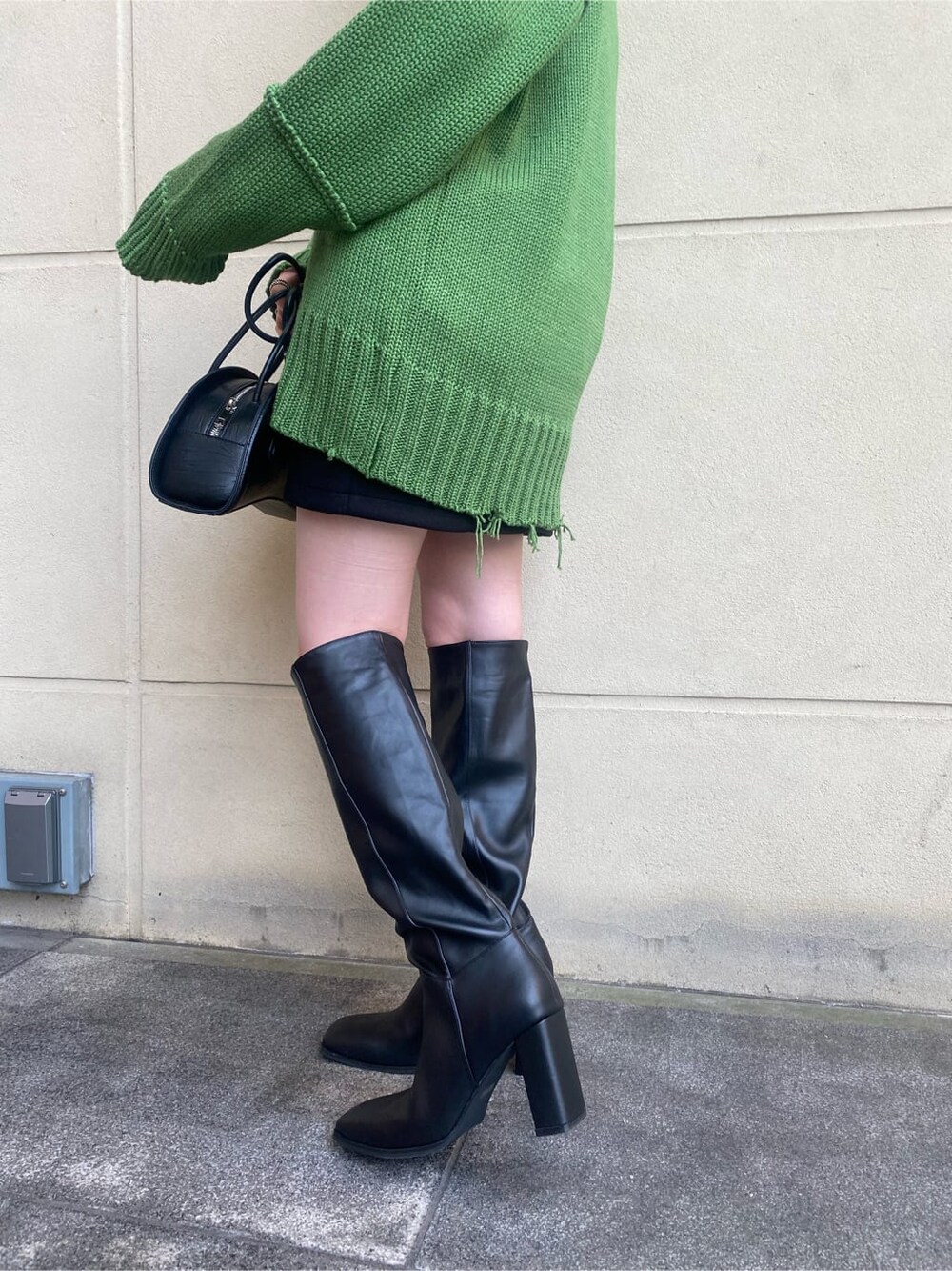 ブラック系のスカート、ブラック系のブーツ、ホワイト系のTシャツ/カットソーを着用したレディースの秋コーディネートの4枚目の写真