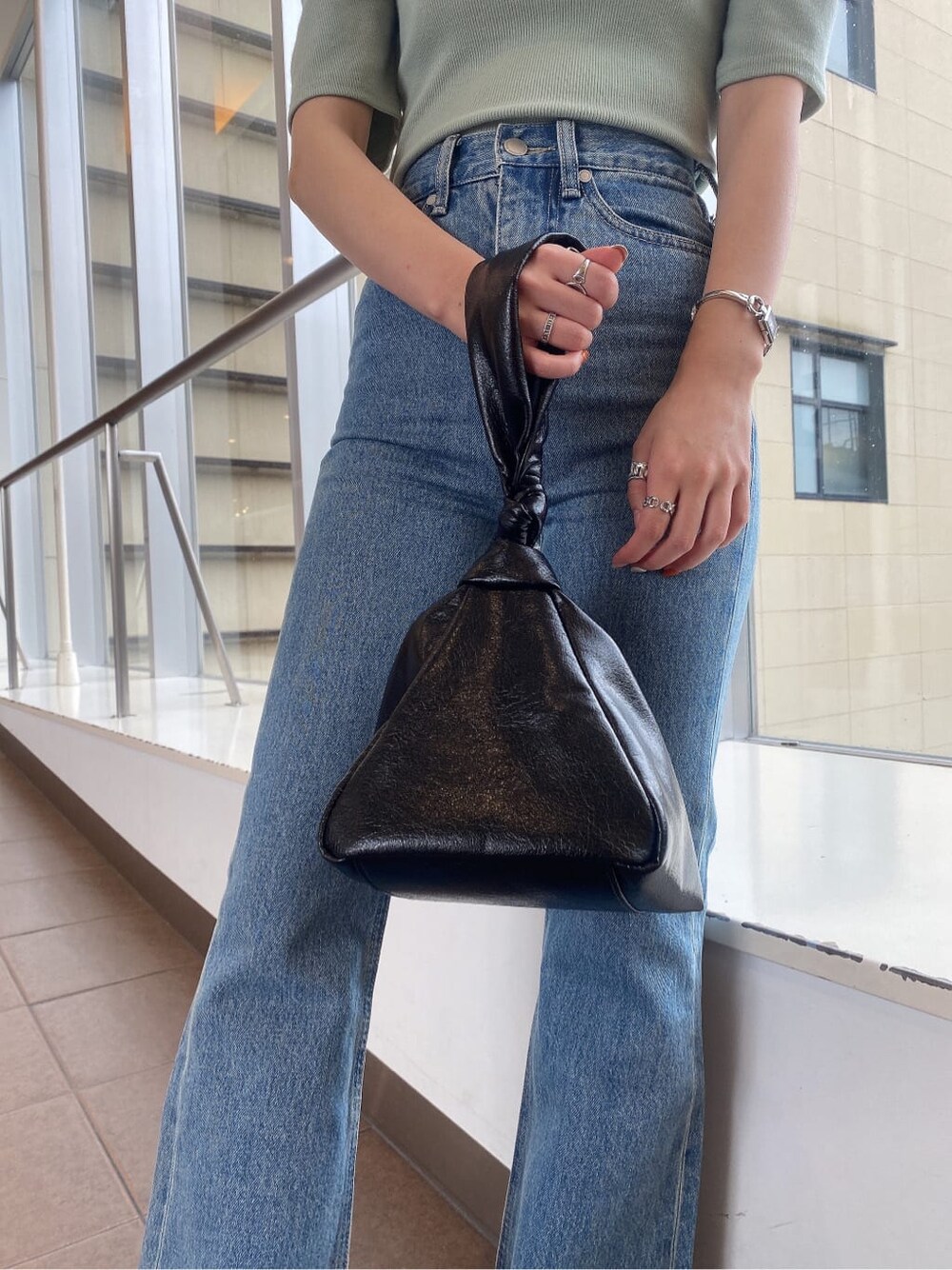 グリーン系のTシャツ/カットソー、ブラック系のハンドバッグ、ブルー系のデニムパンツを着用したレディースの夏コーディネートの6枚目の写真