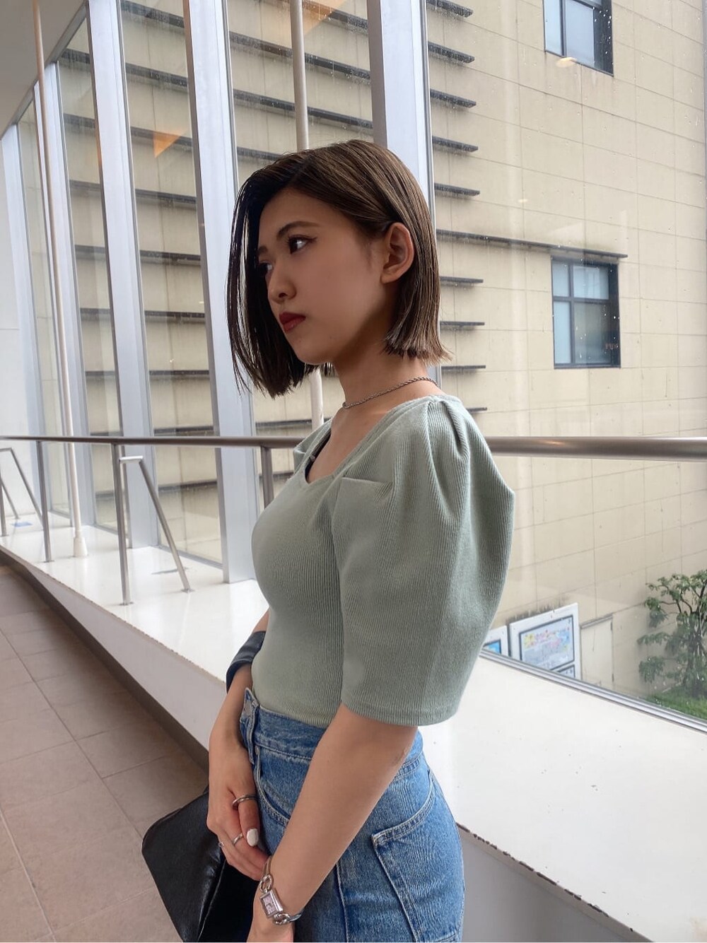 ブラック系のサンダル、グリーン系のTシャツ/カットソー、ブラック系のハンドバッグを着用したレディースの夏コーディネートの2枚目の写真