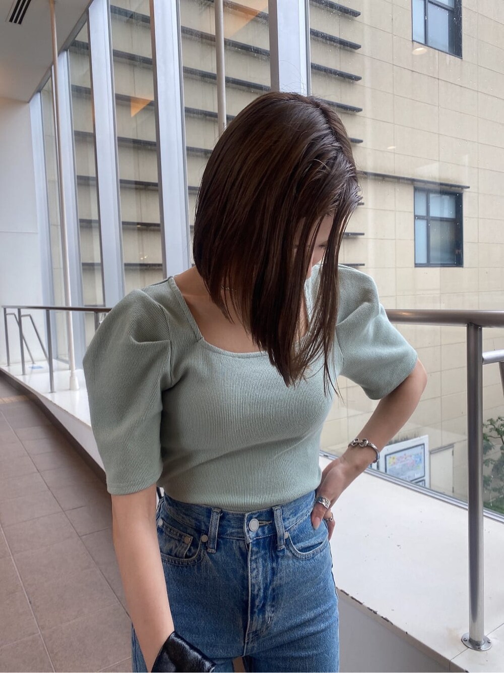 グリーン系のTシャツ/カットソー、ブラック系のハンドバッグ、ブルー系のデニムパンツを着用したレディースの夏コーディネートの4枚目の写真