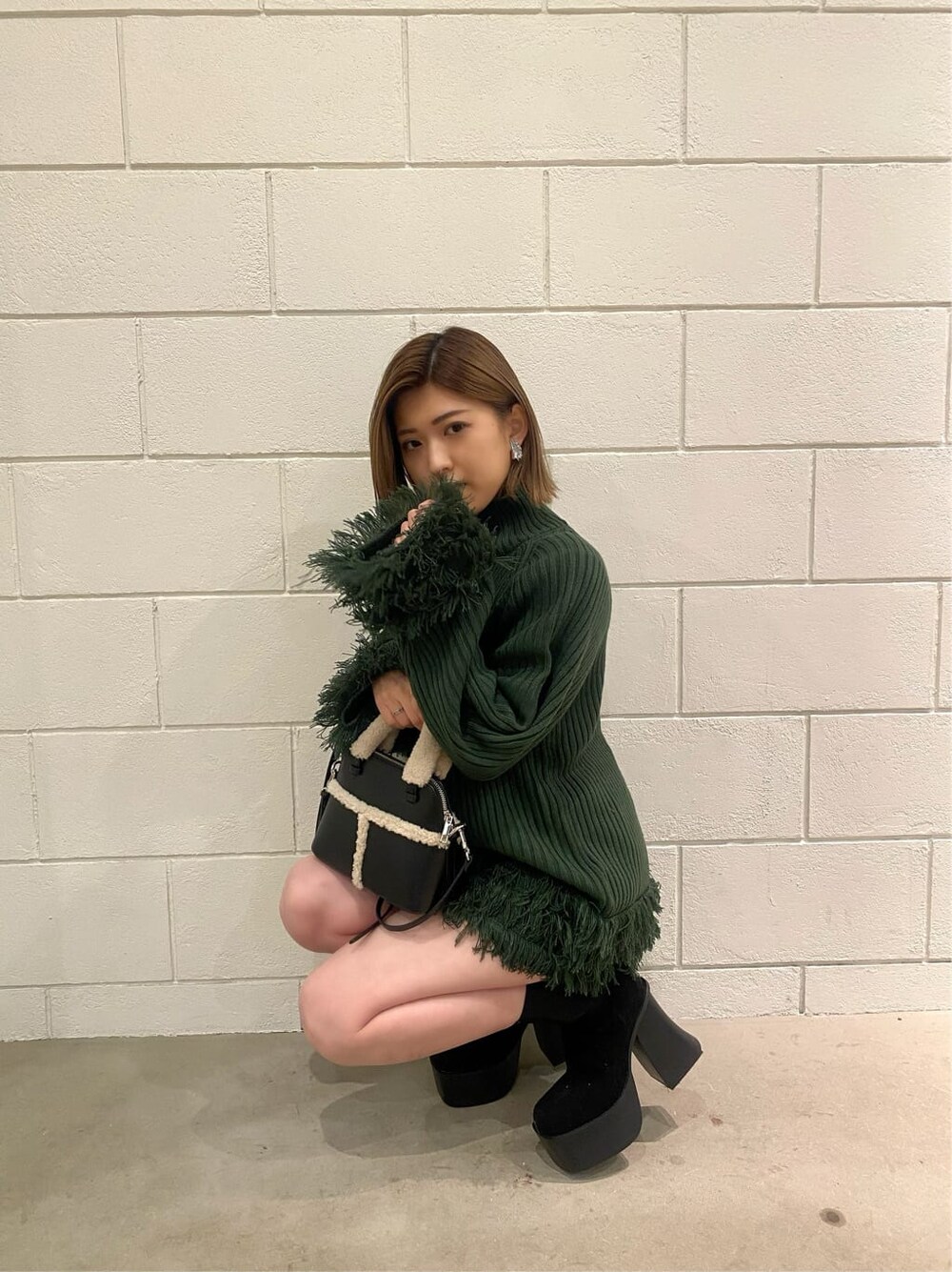 ブラック系のスカート、ブラック系のショルダーバッグ、ブラック系のブーツを着用したレディースの冬コーディネートの4枚目の写真