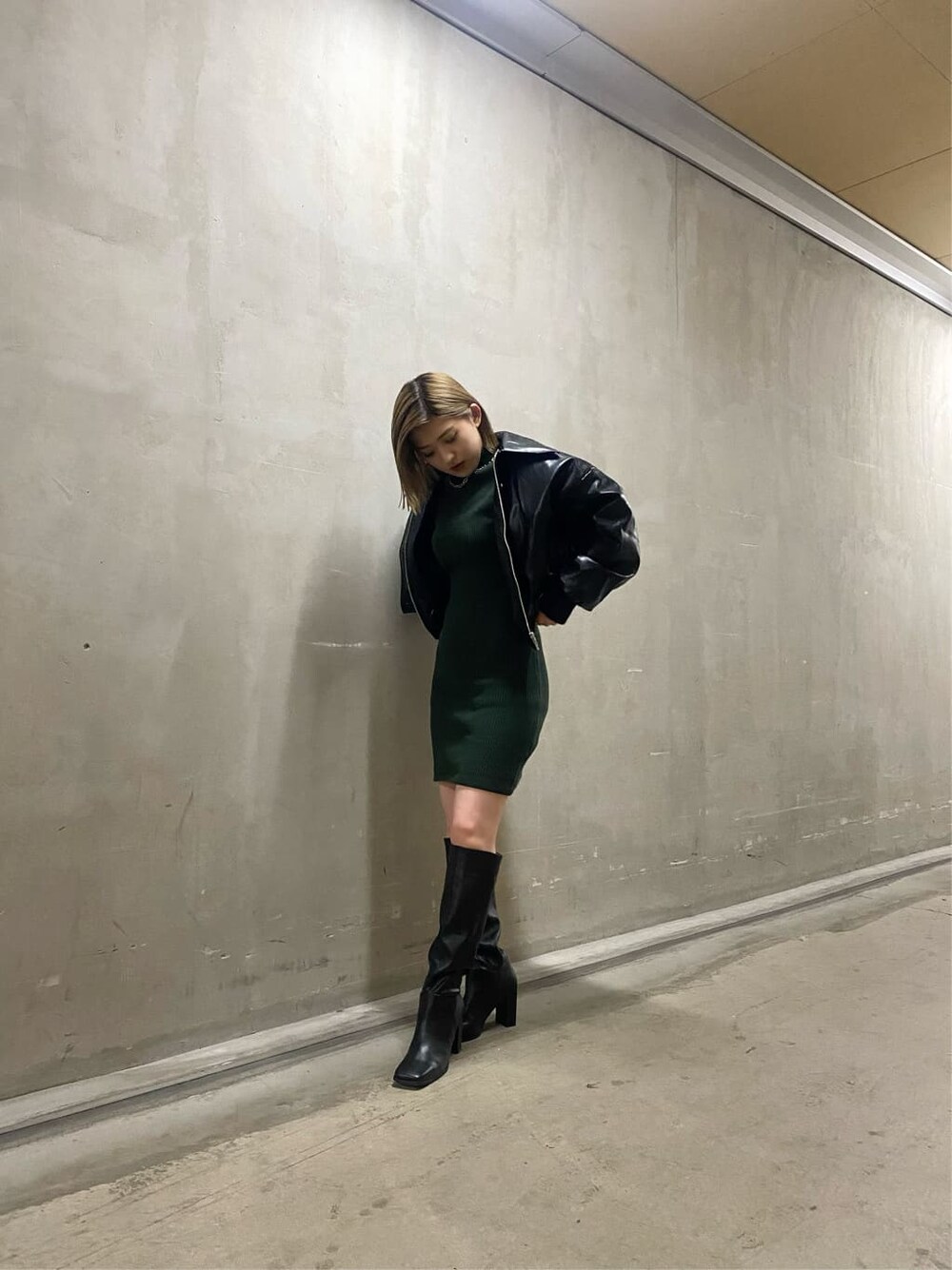 ブラック系のブルゾン、グリーン系のワンピース、ブラック系のブーツを着用したレディースの秋コーディネートの3枚目の写真