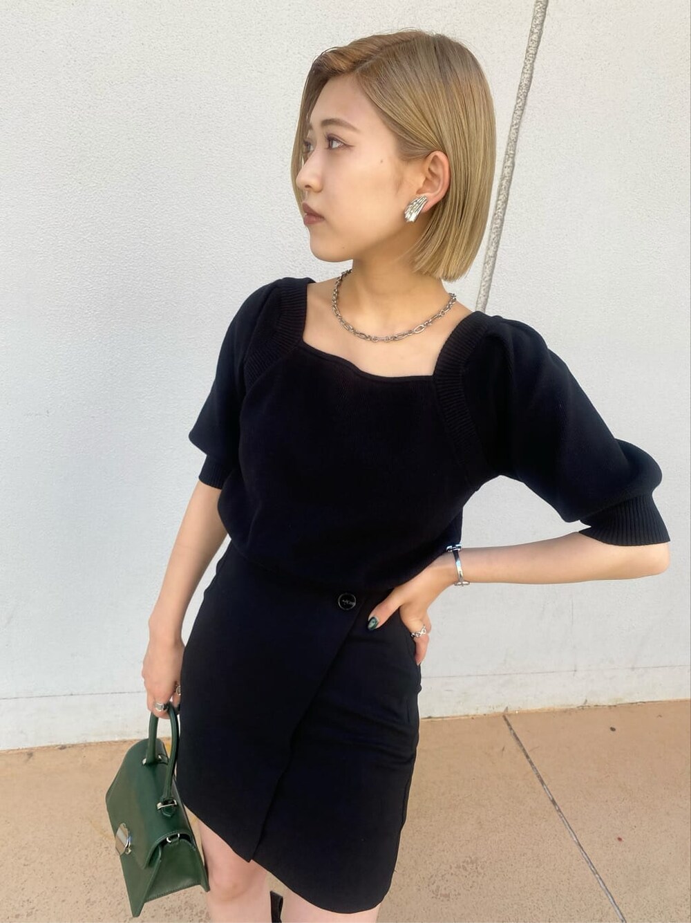 ベージュ系のトレンチコート、ブラック系のスカート、グリーン系のハンドバッグを着用したレディースの夏コーディネートの4枚目の写真