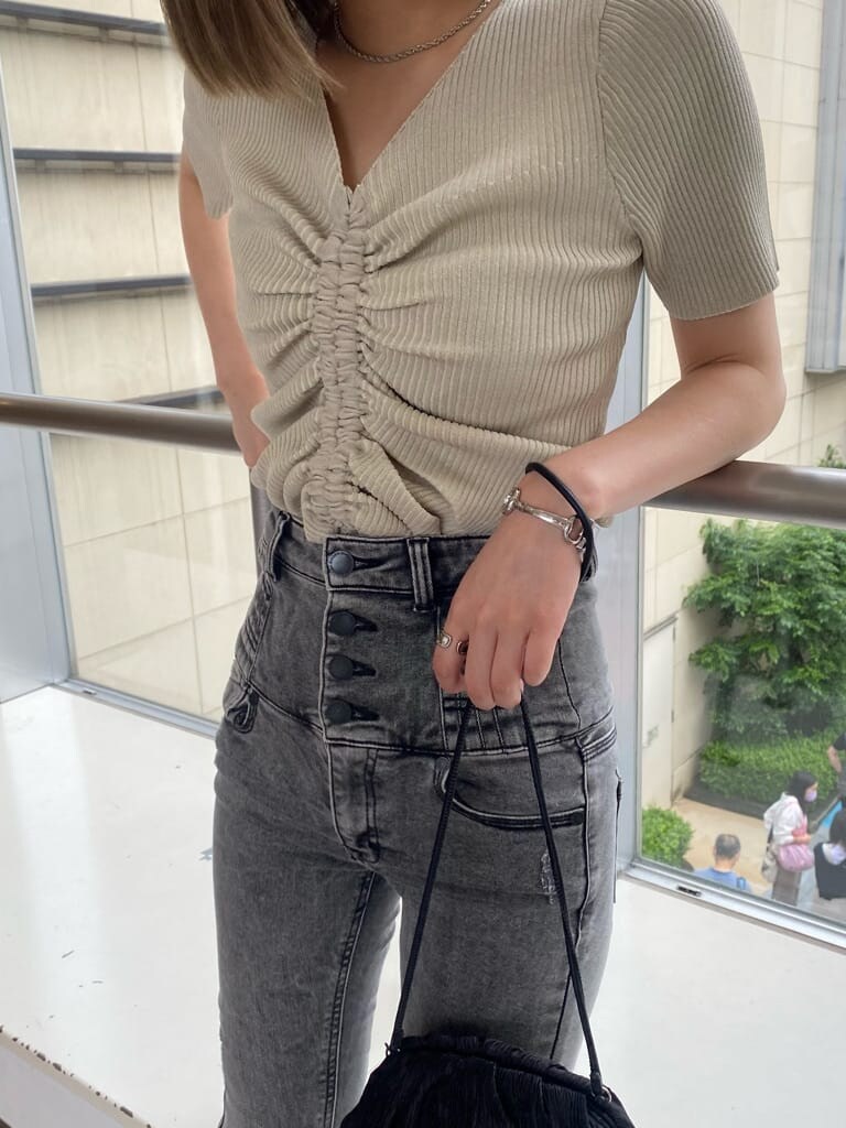 ホワイト系のニット/セーター、ブラック系のデニムパンツ、ブラック系のハンドバッグを着用したレディースの夏コーディネートの2枚目の写真