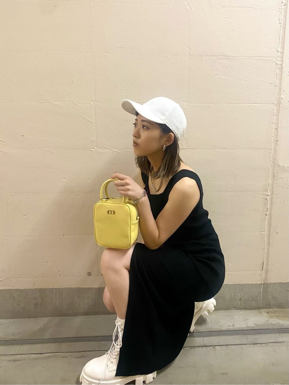 ホワイト系のブーツ、イエロー系のショルダーバッグ、ブラック系のワンピースを着用したレディースの春コーディネートの7枚目の写真