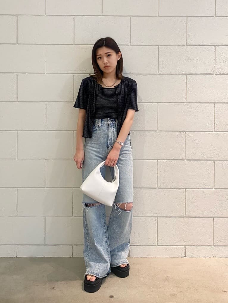 ブラック系のサンダル、ホワイト系のハンドバッグ、ブルー系のデニムパンツを着用したレディースの夏コーディネートの3枚目の写真
