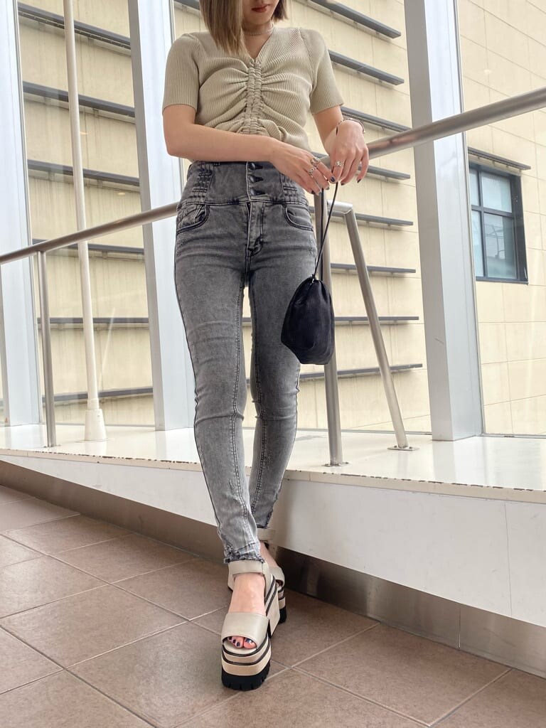 ホワイト系のニット/セーター、ブラック系のデニムパンツ、ブラック系のハンドバッグを着用したレディースの夏コーディネートの4枚目の写真