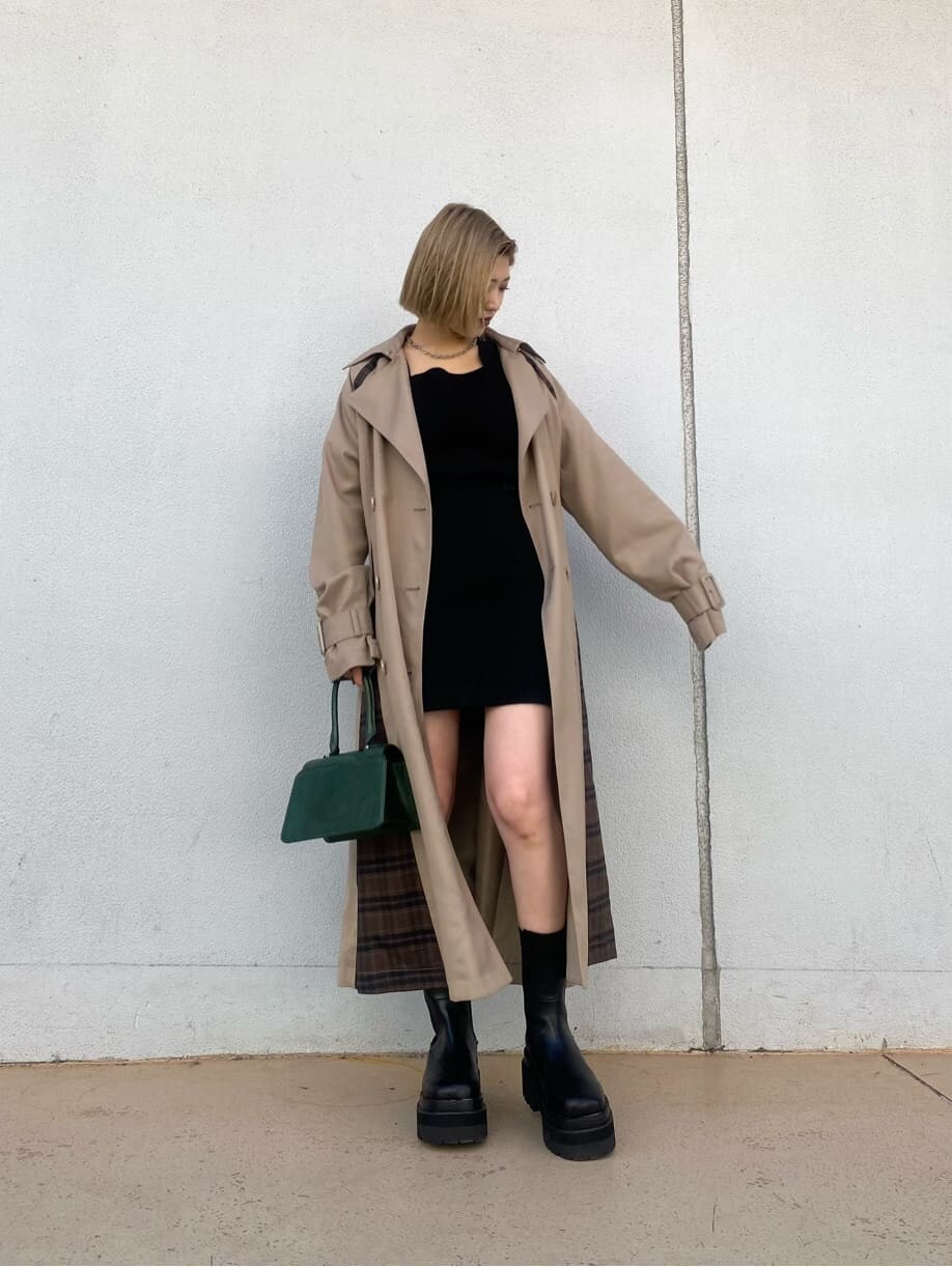 ベージュ系のトレンチコート、ブラック系のスカート、グリーン系のハンドバッグを着用したレディースの夏コーディネートの2枚目の写真
