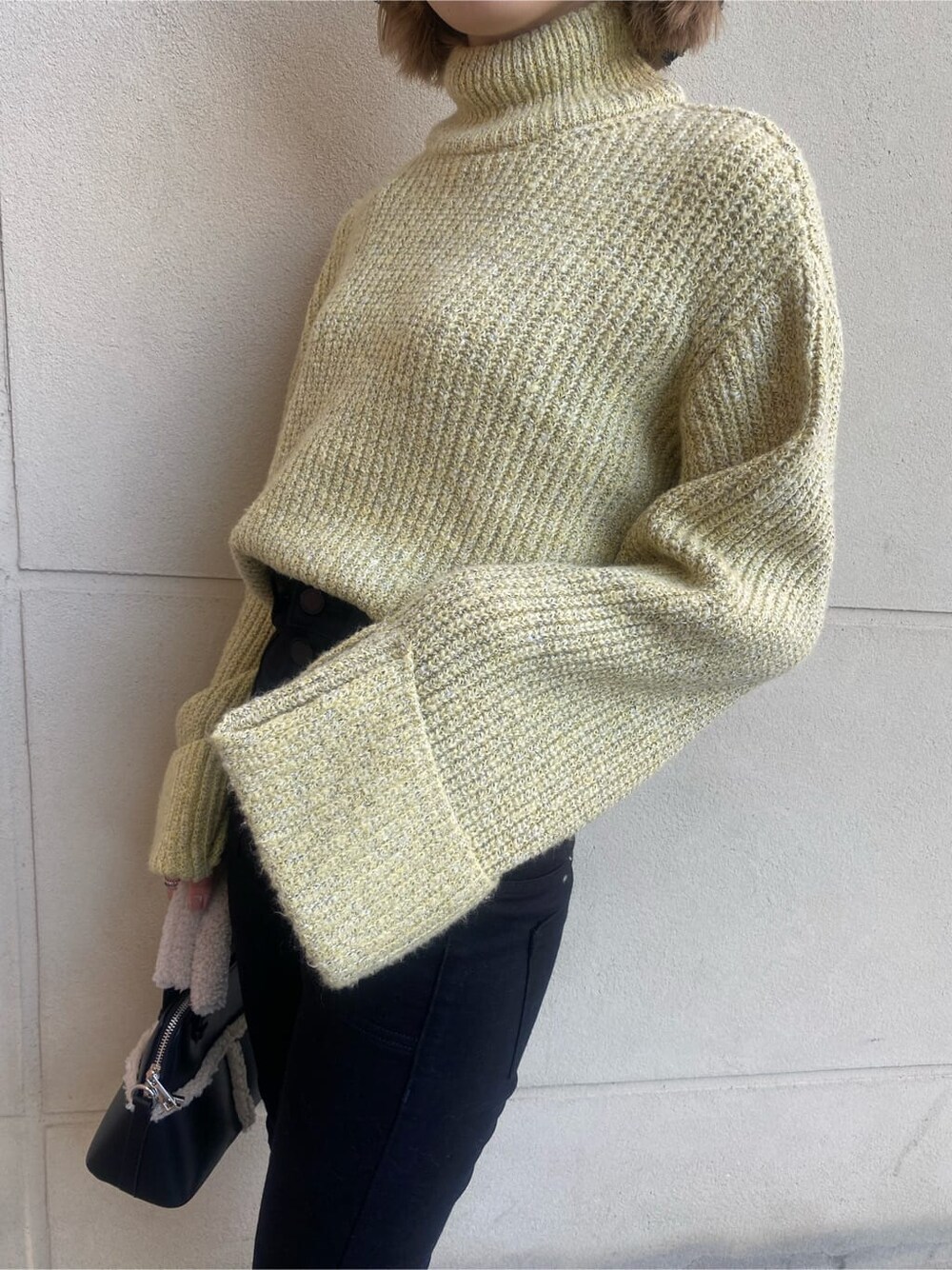 ブラック系のブーツ、ブラック系のハンドバッグ、イエロー系のニット/セーターを着用したレディースの秋コーディネートの4枚目の写真