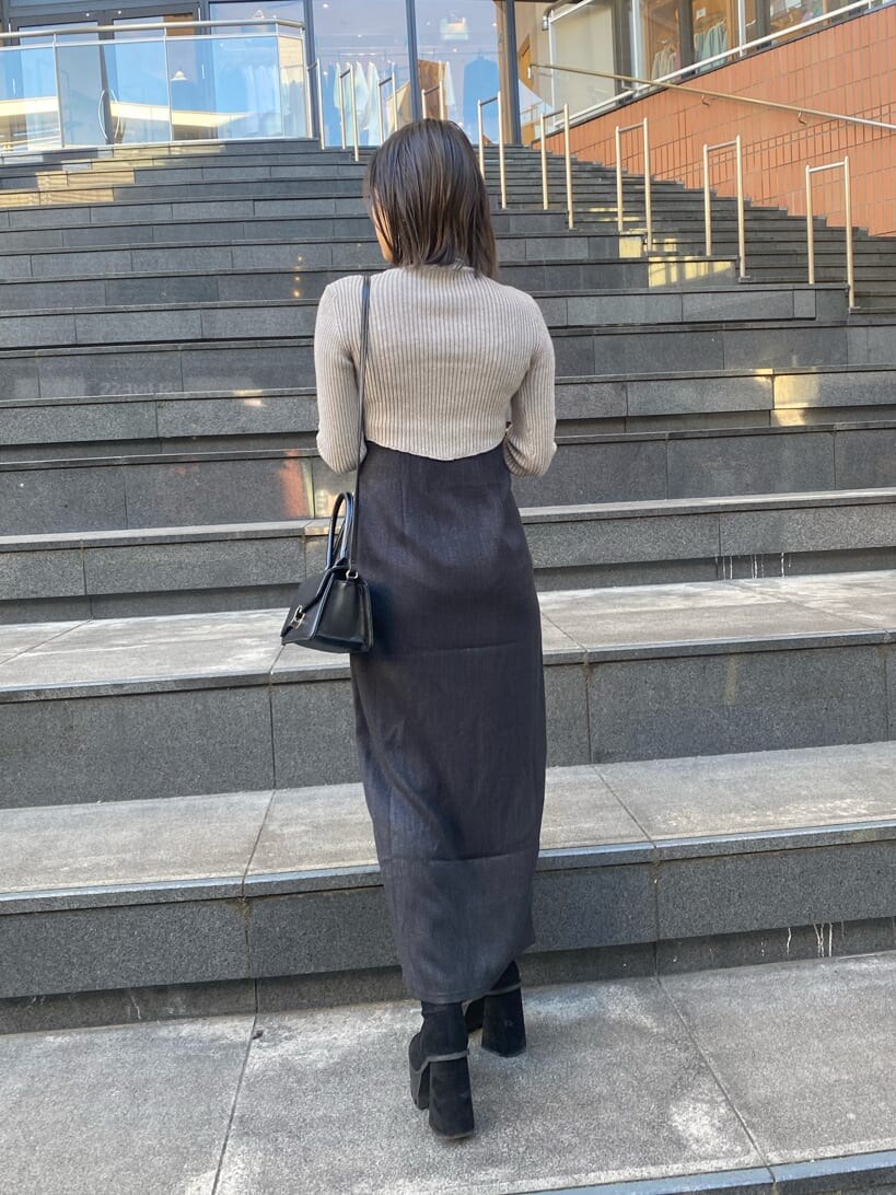 グレー系のニット/セーター、ブラック系のブーツ、ブラック系のスカートを着用したレディースの冬コーディネートの5枚目の写真