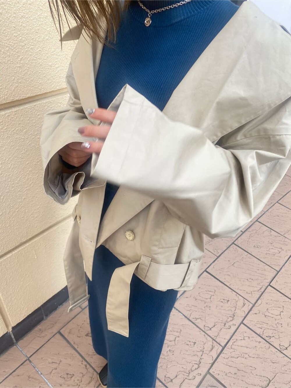 ブルー系のワンピース、ベージュ系のトレンチコート、ブラック系のブーツを着用したレディースの冬コーディネートの5枚目の写真