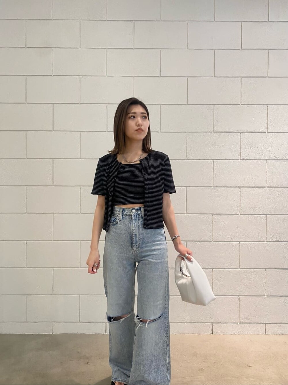 ブラック系のサンダル、ホワイト系のハンドバッグ、ブルー系のデニムパンツを着用したレディースの夏コーディネートの7枚目の写真