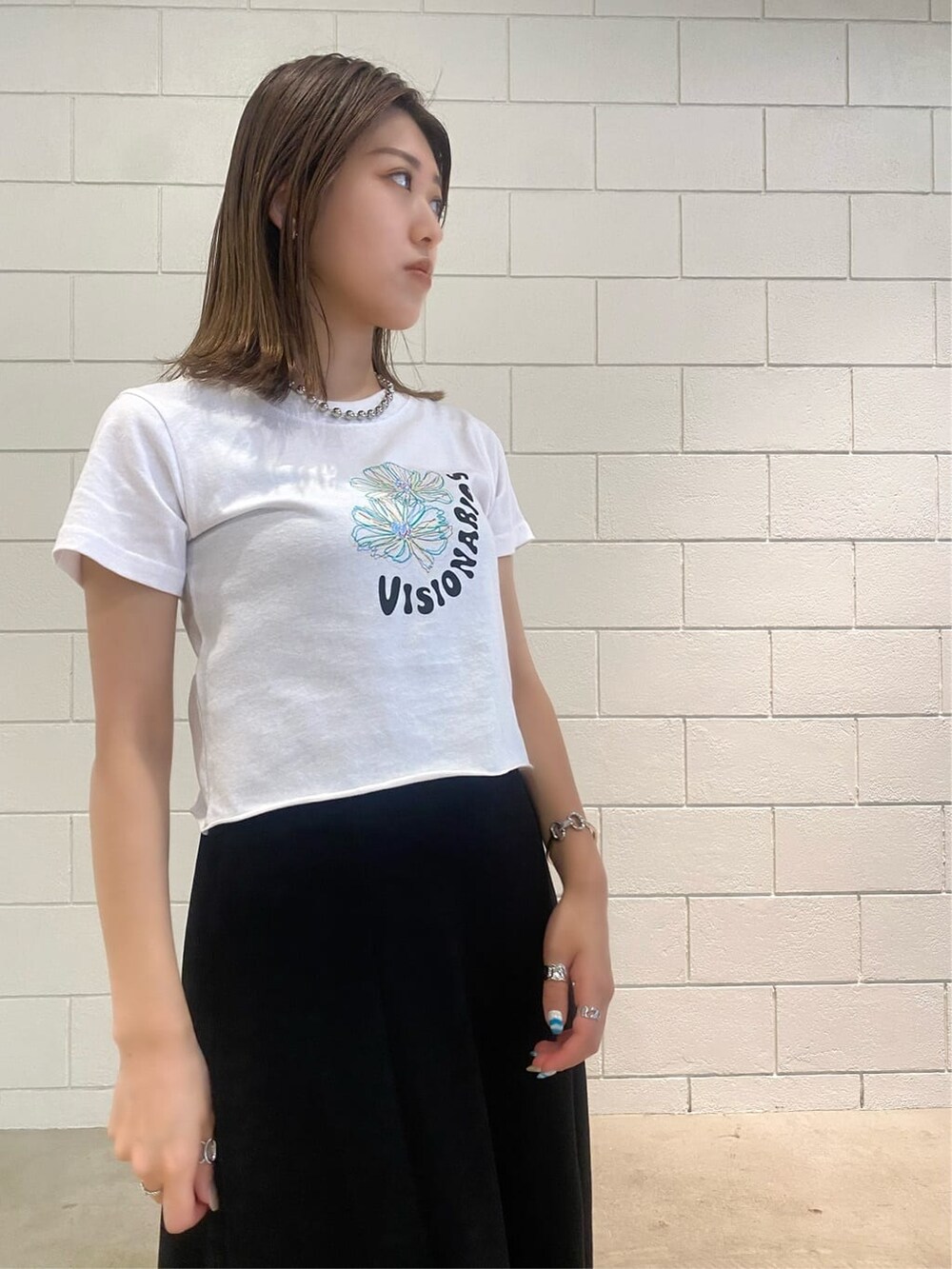 ブラック系のスカート、ブラック系のサンダル、ホワイト系のTシャツ/カットソーを着用したレディースの夏コーディネートの9枚目の写真