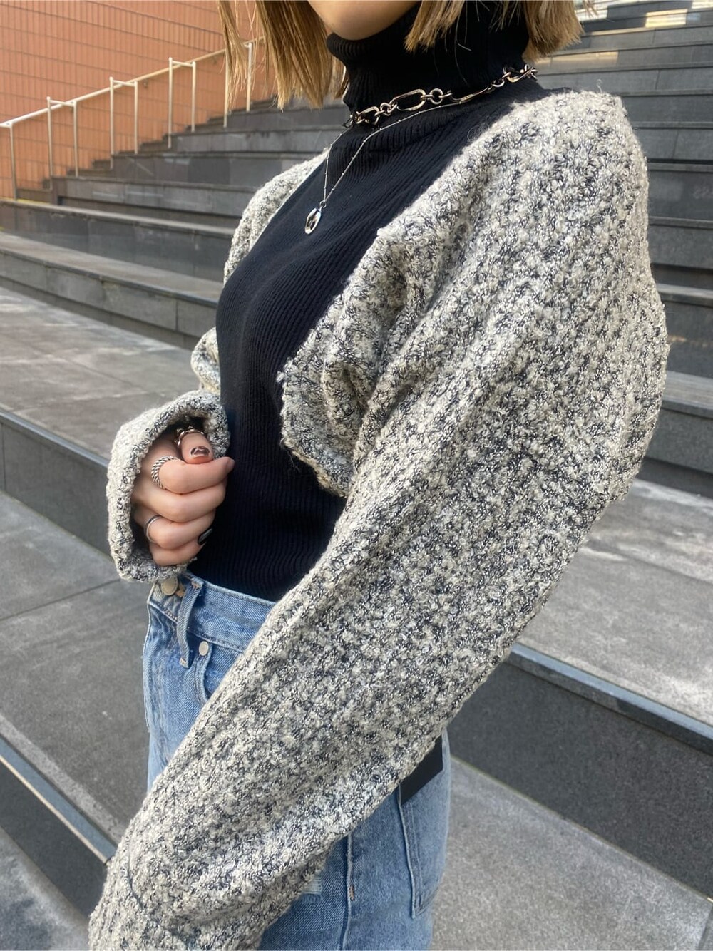 ブルー系のデニムパンツ、ブラック系のニット/セーター、ブラック系のチェスターコートを着用したレディースの秋コーディネートの8枚目の写真
