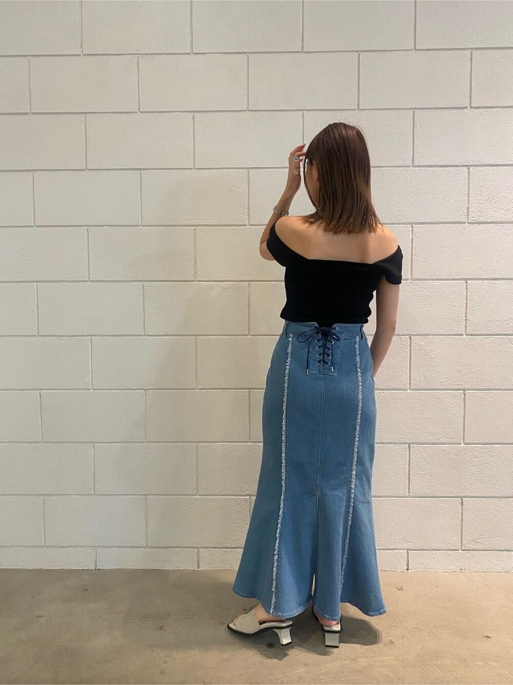 ブラウン系のハンドバッグ、ブルー系のスカート、ブラック系のタンクトップを着用したレディースの夏コーディネートの4枚目の写真