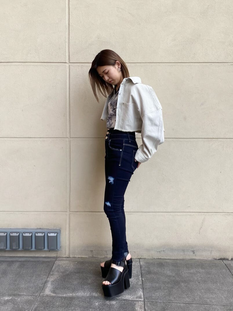 ブルー系のデニムパンツ、ホワイト系のデニムジャケット、ブラック系のサンダルを着用したレディースの春コーディネートの2枚目の写真