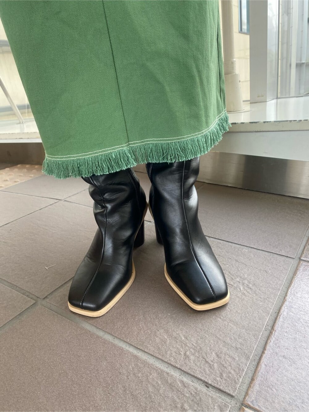 ブラック系のニット/セーター、ブラック系のブーツ、ブラック系のハンドバッグを着用したレディースの冬コーディネートの8枚目の写真