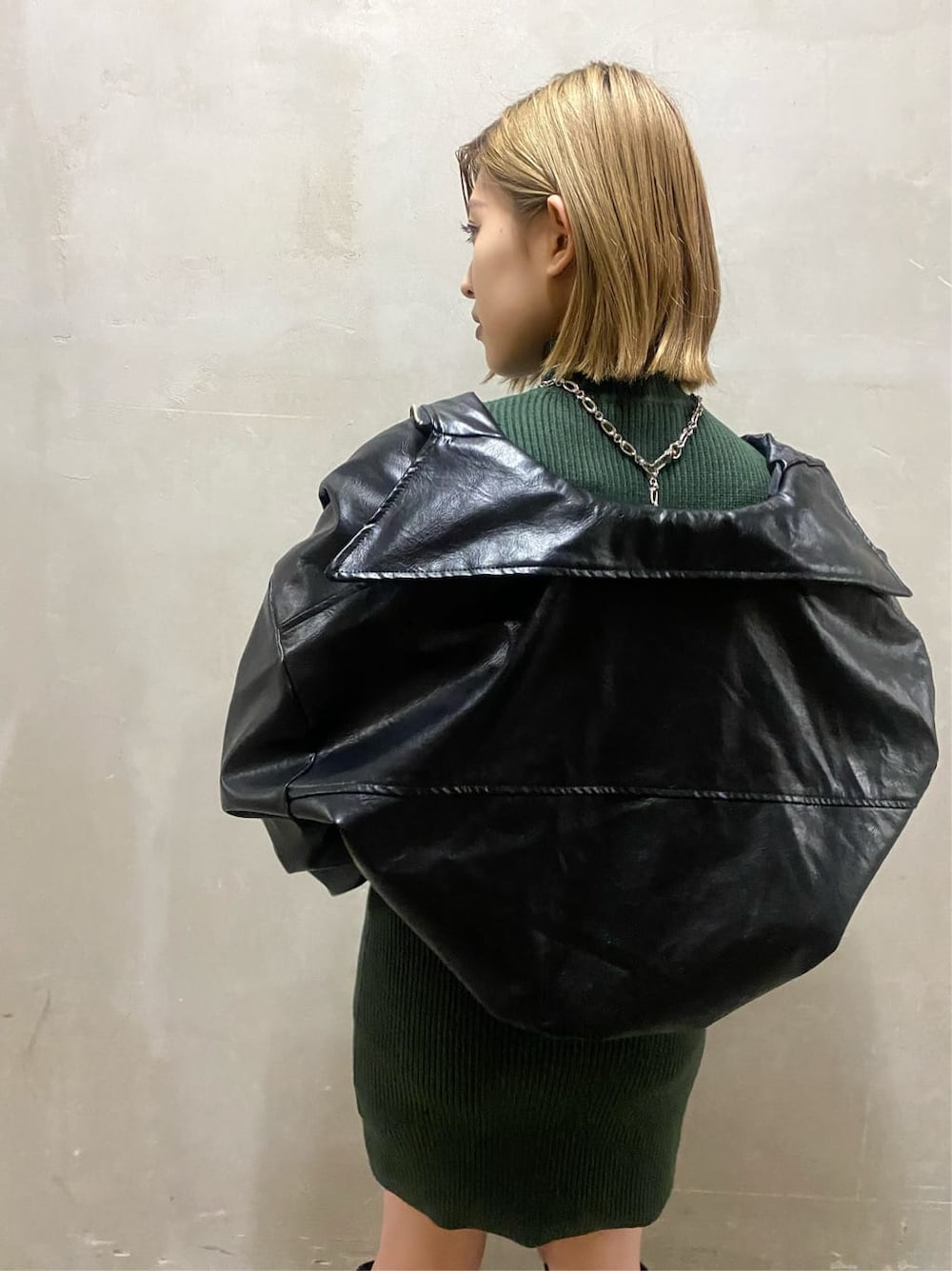 ブラック系のブルゾン、グリーン系のワンピース、ブラック系のブーツを着用したレディースの秋コーディネートの2枚目の写真