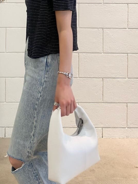 ブラック系のサンダル、ホワイト系のハンドバッグ、ブルー系のデニムパンツを着用したレディースの夏コーディネートの8枚目の写真