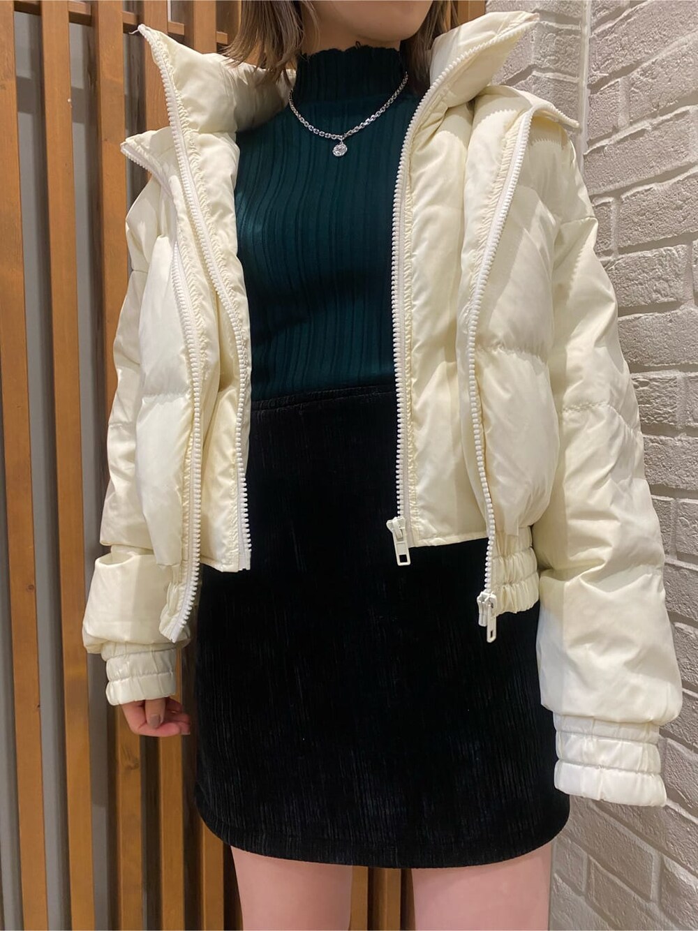 ブラック系のスカート、ホワイト系のダウンジャケット/コート、グリーン系のニット/セーターを着用したレディースの冬コーディネートの7枚目の写真