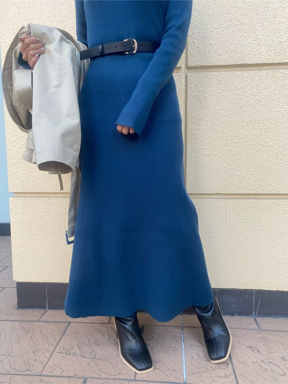 ブルー系のワンピース、ベージュ系のトレンチコート、ブラック系のブーツを着用したレディースの冬コーディネートの4枚目の写真