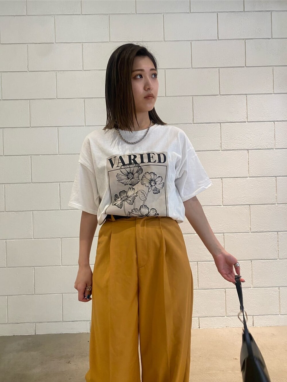 オレンジ系のその他パンツ、ブラック系のハンドバッグ、ホワイト系のTシャツ/カットソーを着用したレディースの春コーディネートの5枚目の写真