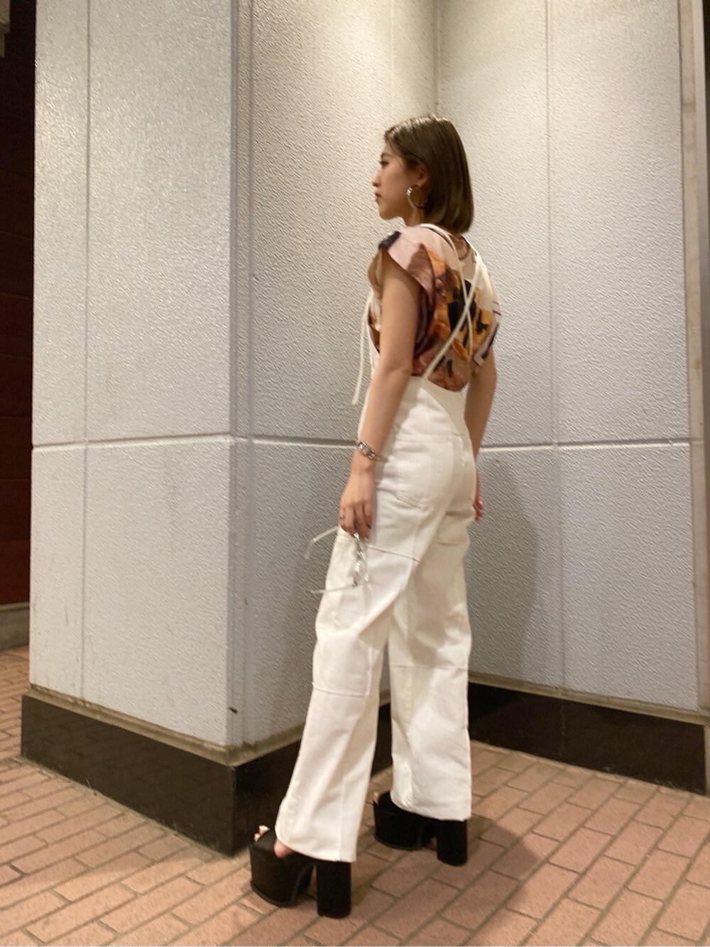 ホワイト系のサロペット/オーバーオール、ブラック系のサンダル、ベージュ系のTシャツ/カットソーを着用したレディースの夏コーディネートの2枚目の写真