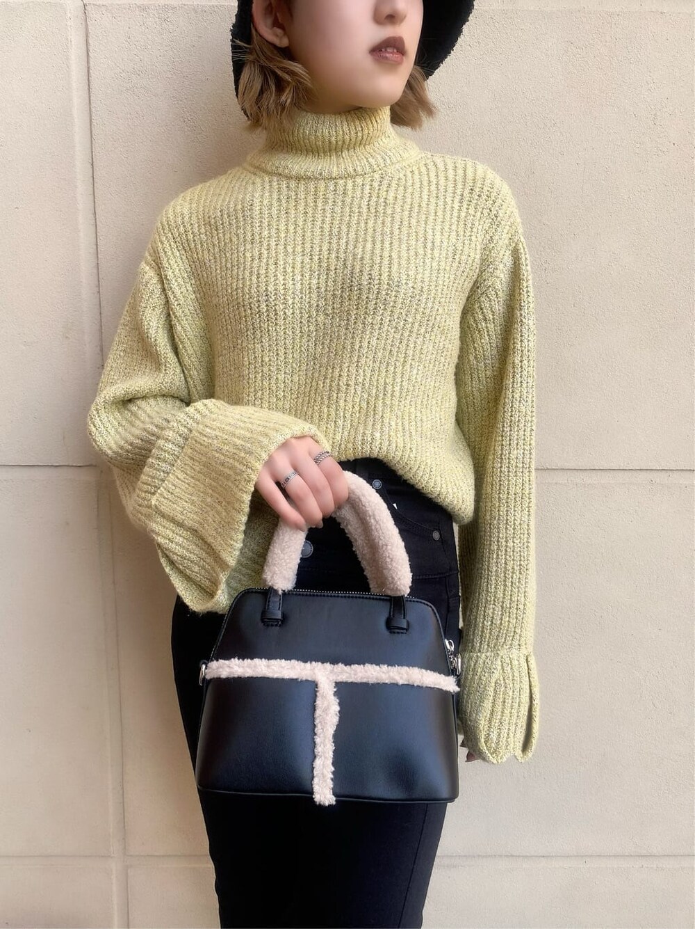 ブラック系のブーツ、ブラック系のハンドバッグ、イエロー系のニット/セーターを着用したレディースの秋コーディネートの3枚目の写真