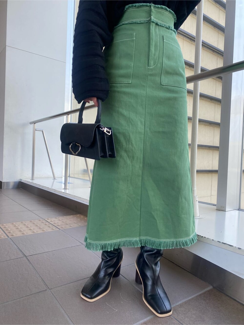 ブラック系のニット/セーター、ブラック系のブーツ、ブラック系のハンドバッグを着用したレディースの冬コーディネートの7枚目の写真