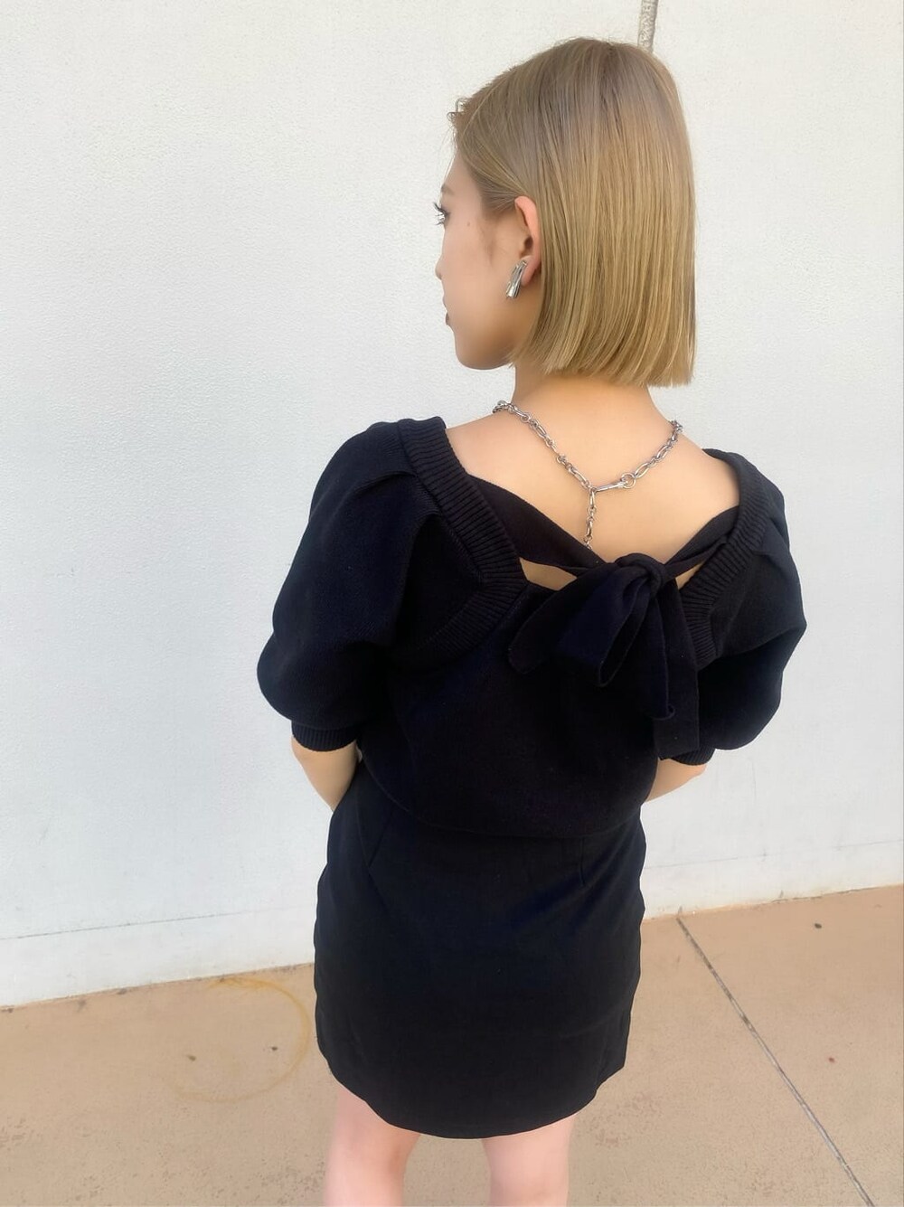 ベージュ系のトレンチコート、ブラック系のスカート、グリーン系のハンドバッグを着用したレディースの夏コーディネートの6枚目の写真