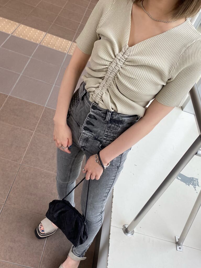 ホワイト系のニット/セーター、ブラック系のデニムパンツ、ブラック系のハンドバッグを着用したレディースの夏コーディネートの5枚目の写真