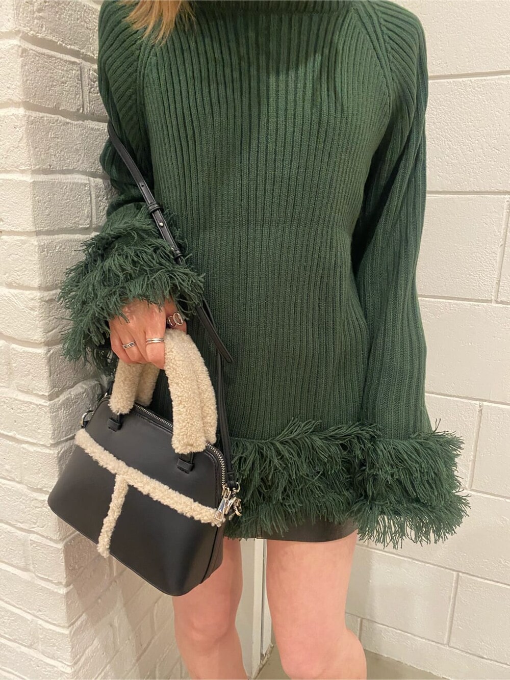 ブラック系のスカート、ブラック系のショルダーバッグ、ブラック系のブーツを着用したレディースの冬コーディネートの5枚目の写真