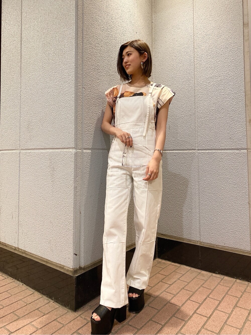 ホワイト系のサロペット/オーバーオール、ブラック系のサンダル、ベージュ系のTシャツ/カットソーを着用したレディースの夏コーディネートの5枚目の写真
