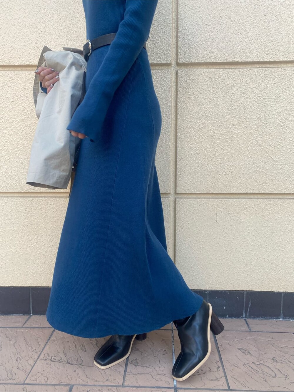 ブルー系のワンピース、ベージュ系のトレンチコート、ブラック系のブーツを着用したレディースの冬コーディネートの3枚目の写真