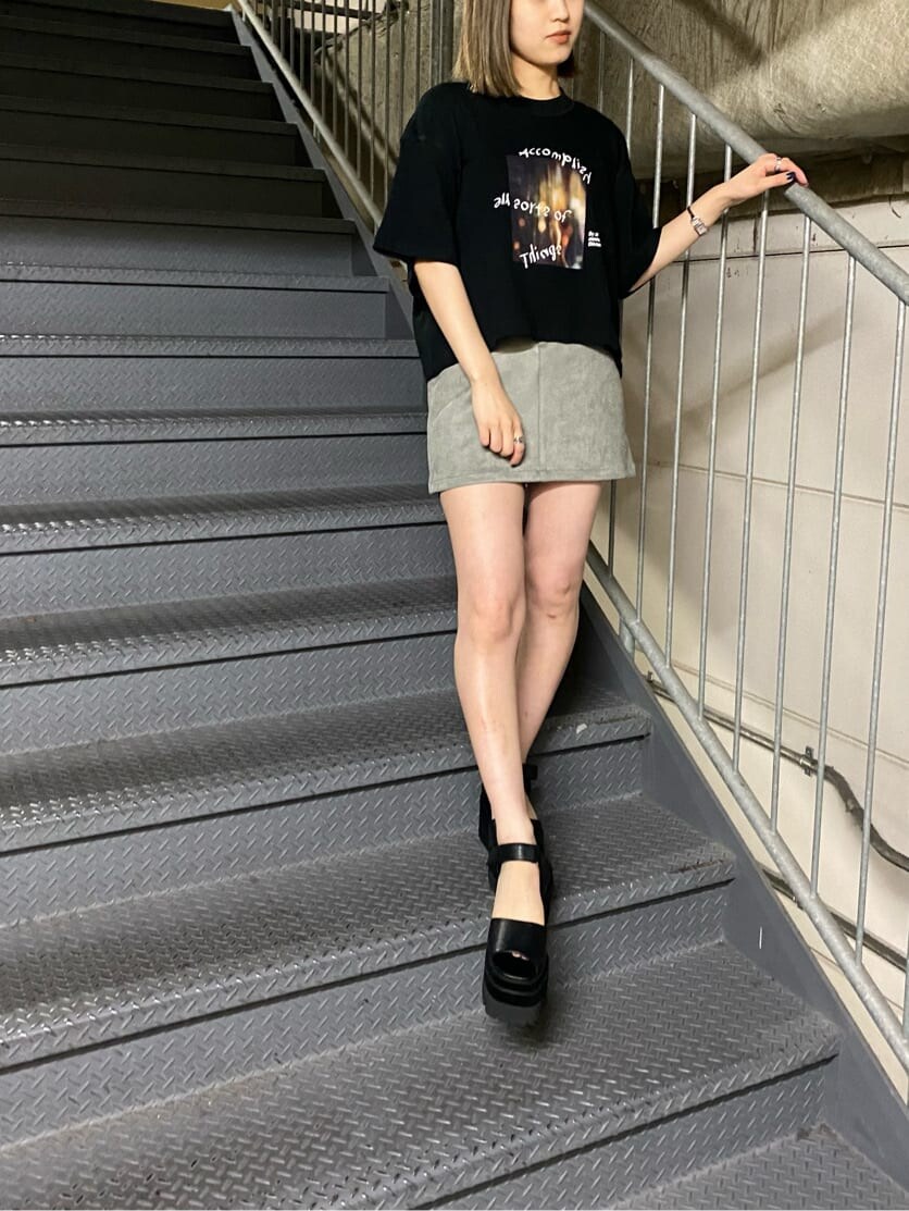 グレー系のスカート、ブラック系のサンダル、ブラック系のTシャツ/カットソーを着用したレディースの夏コーディネートの2枚目の写真