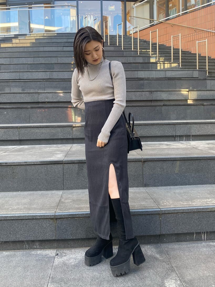 グレー系のニット/セーター、ブラック系のブーツ、ブラック系のスカートを着用したレディースの冬コーディネートの2枚目の写真