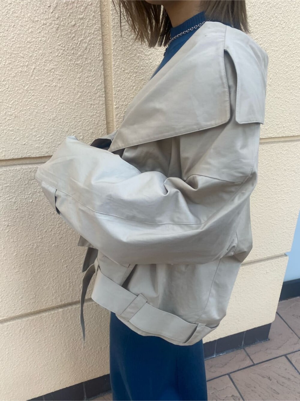 ブルー系のワンピース、ベージュ系のトレンチコート、ブラック系のブーツを着用したレディースの冬コーディネートの7枚目の写真