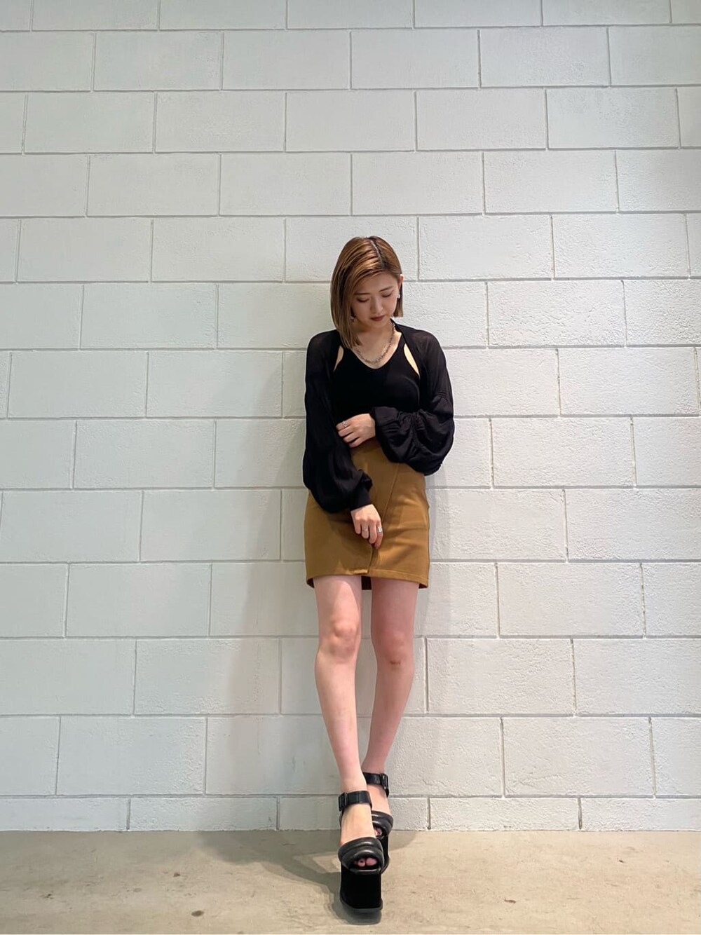 イエロー系のスカート、ブラック系のサンダル、ブラック系のカーディガン/ボレロを着用したレディースの夏コーディネートの2枚目の写真