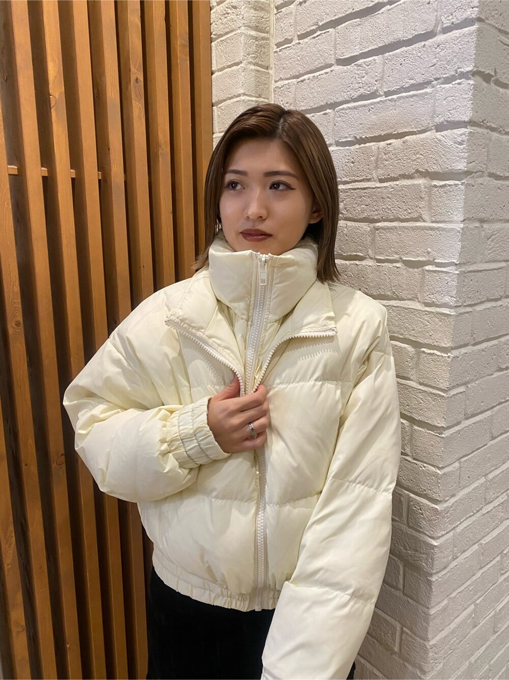 ブラック系のスカート、ホワイト系のダウンジャケット/コート、グリーン系のニット/セーターを着用したレディースの冬コーディネートの4枚目の写真