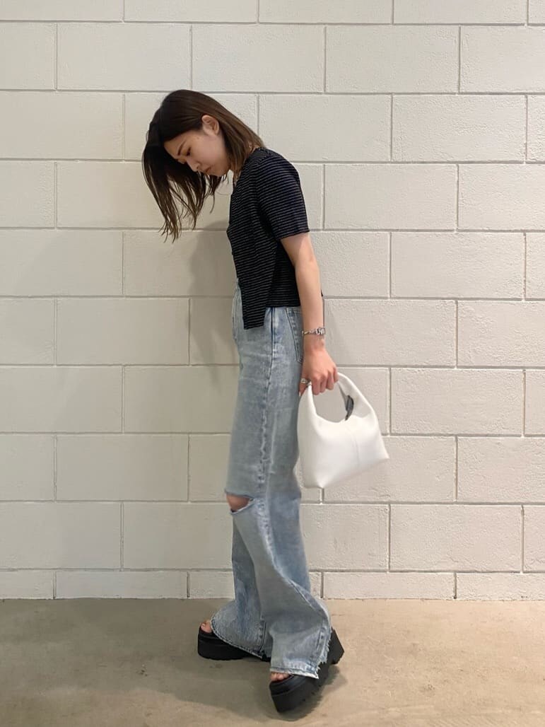 ブラック系のサンダル、ホワイト系のハンドバッグ、ブルー系のデニムパンツを着用したレディースの夏コーディネートの4枚目の写真