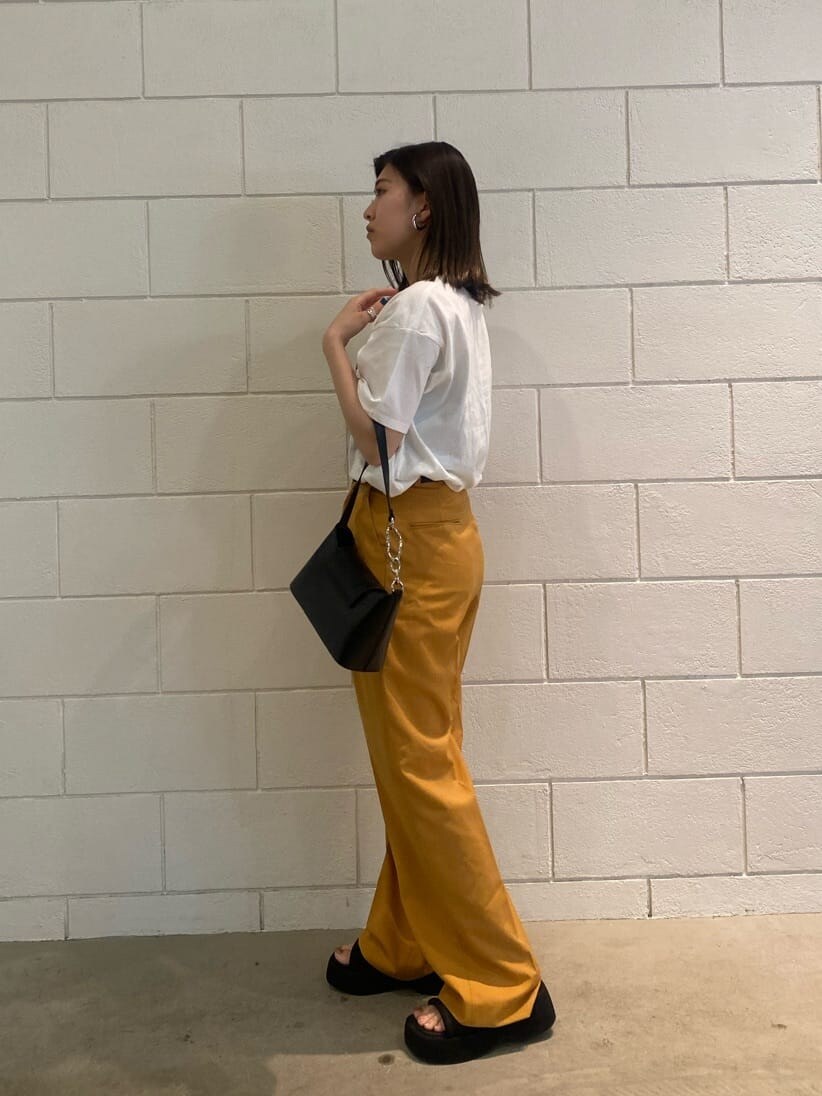 オレンジ系のその他パンツ、ブラック系のハンドバッグ、ホワイト系のTシャツ/カットソーを着用したレディースの春コーディネートの2枚目の写真