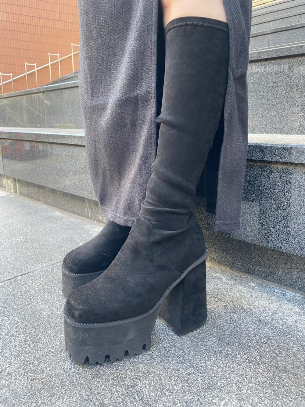 グレー系のニット/セーター、ブラック系のブーツ、ブラック系のスカートを着用したレディースの冬コーディネートの7枚目の写真