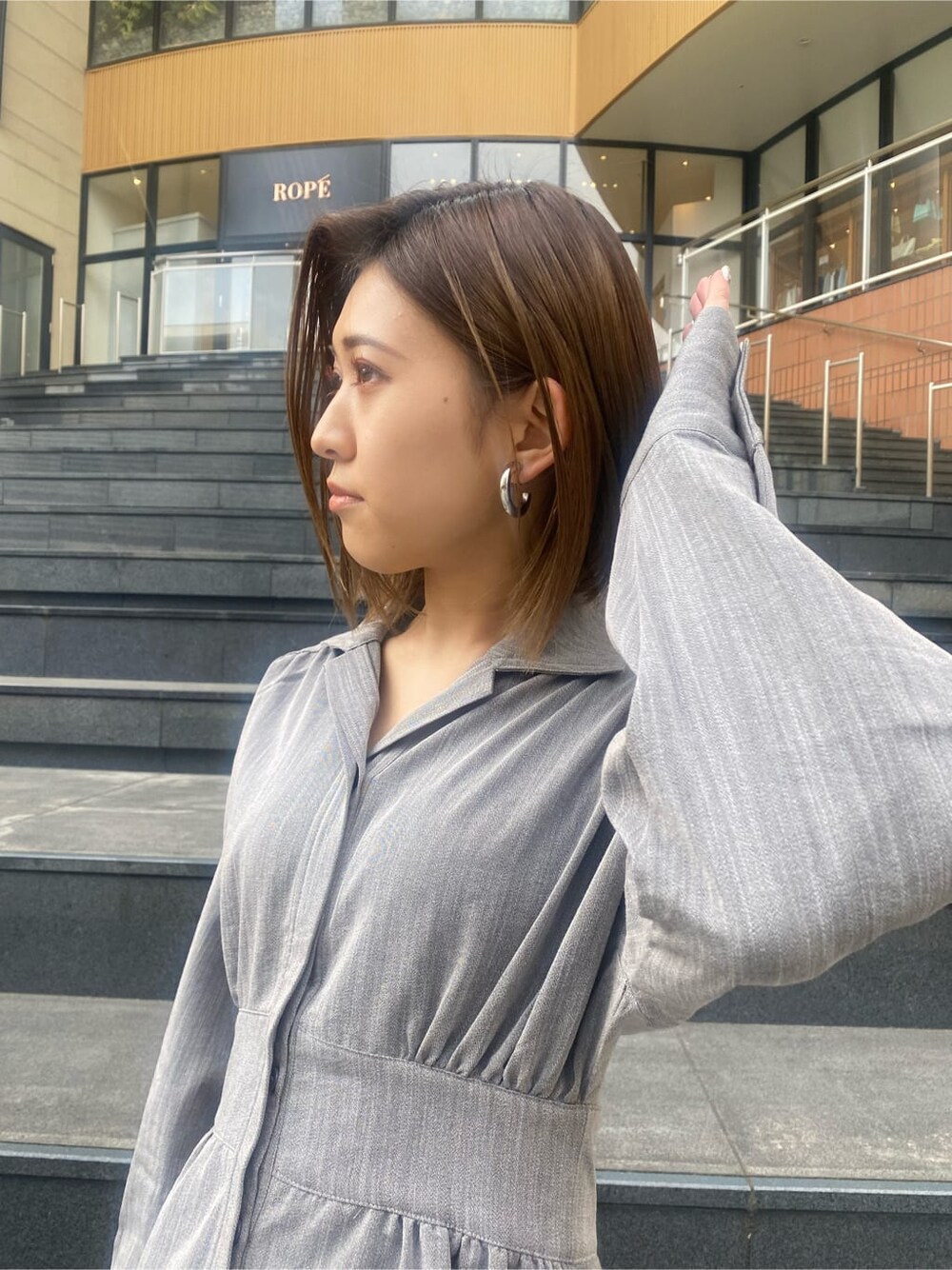 グレー系のシャツワンピース、ブラック系のブーツを着用したレディースの冬コーディネートの4枚目の写真