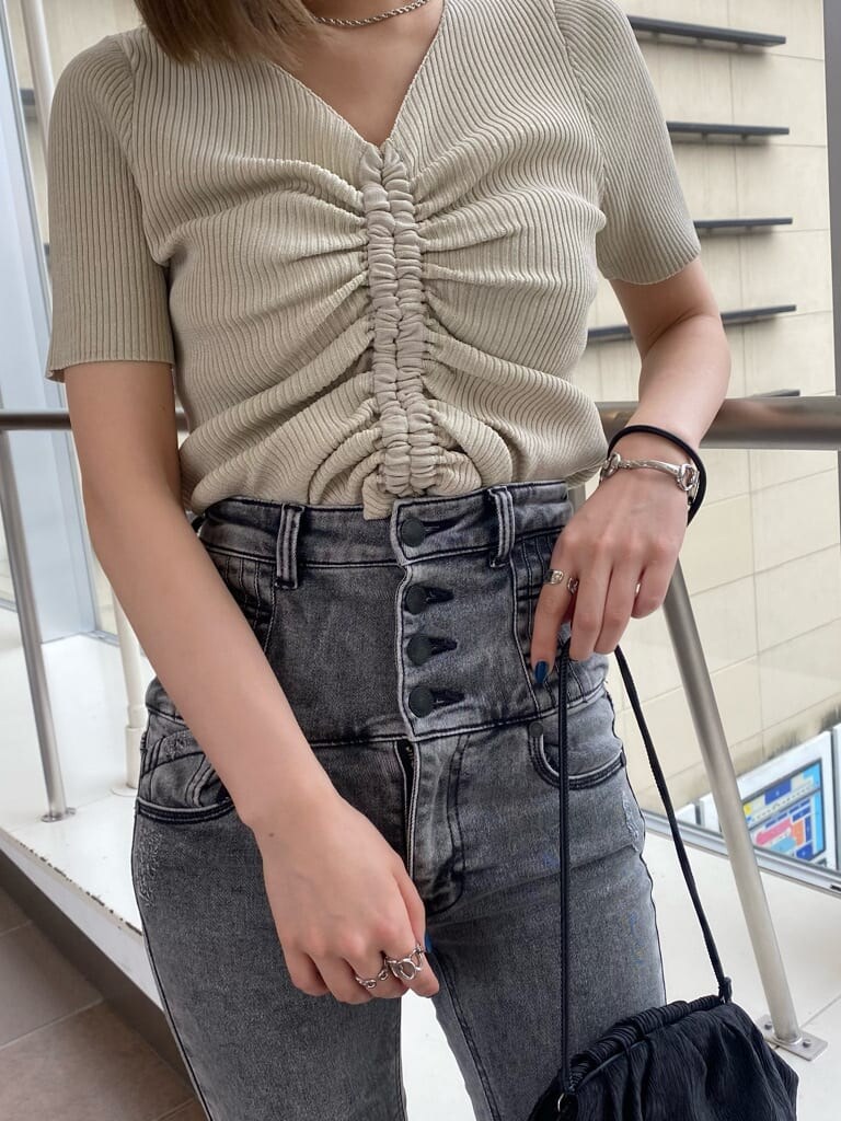 ホワイト系のニット/セーター、ブラック系のデニムパンツ、ブラック系のハンドバッグを着用したレディースの夏コーディネートの6枚目の写真