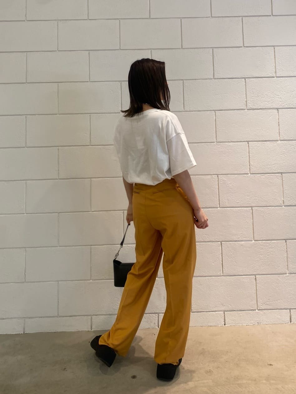 オレンジ系のその他パンツ、ブラック系のハンドバッグ、ホワイト系のTシャツ/カットソーを着用したレディースの春コーディネートの3枚目の写真